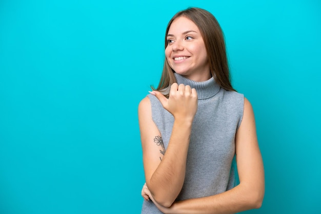 Young Lithuanian woman isolated on blue background pointing to the side to present a product