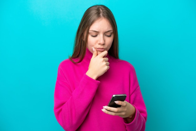 Young Lithuanian woman isolated on blue background thinking and sending a message