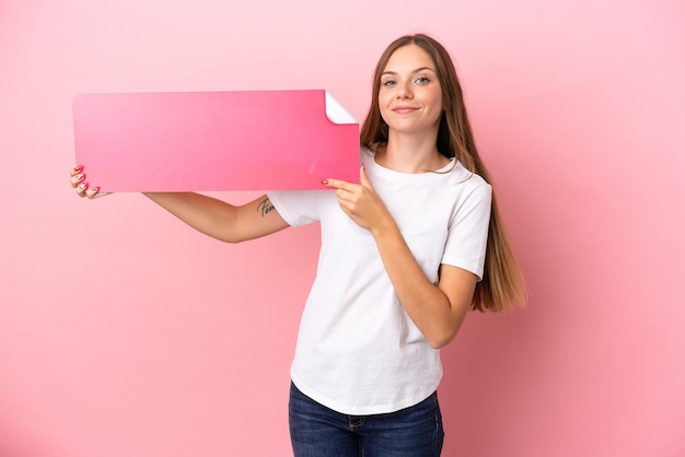 Young Lithuanian woman isolated on pink background holding an empty placard