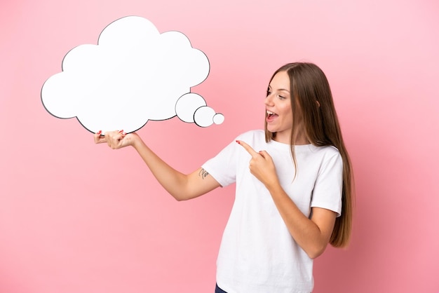 Young Lithuanian woman isolated on pink background holding a thinking speech bubble and pointing it