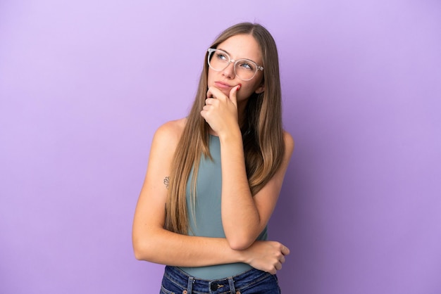 Young Lithuanian woman isolated on purple background having doubts