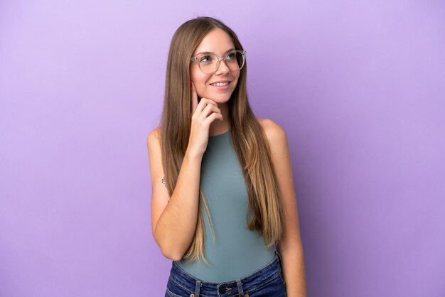 Young Lithuanian woman isolated on purple background thinking an idea while looking up