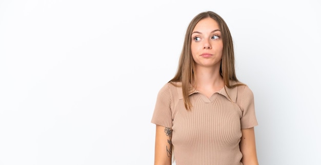 Young Lithuanian woman isolated on white background making doubts gesture looking side