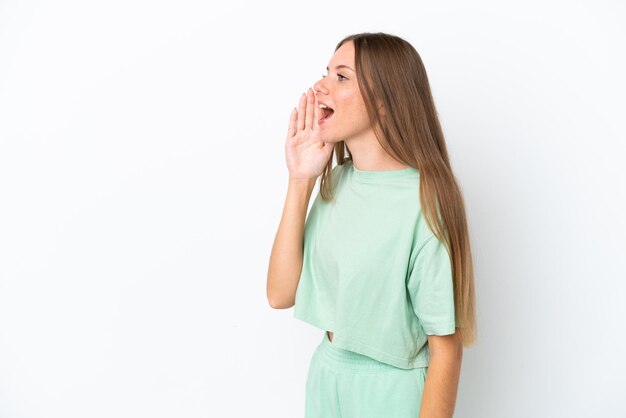 Young Lithuanian woman isolated on white background shouting with mouth wide open to the side