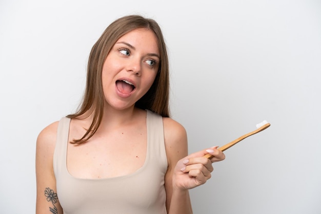 Young Lithuanian woman isolated on white background with a toothbrush and surprised expression