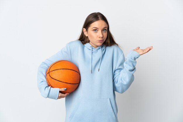 Young Lithuanian woman playing basketball isolated on white background having doubts while raising hands