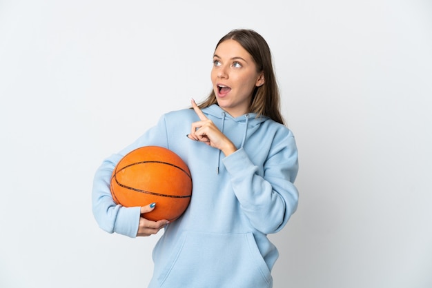 Young Lithuanian woman playing basketball isolated on white wall intending to realizes the solution while lifting a finger up