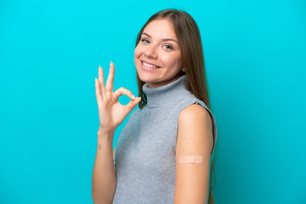 Young Lithuanian woman wearing band aids isolated on blue background showing ok sign with fingers