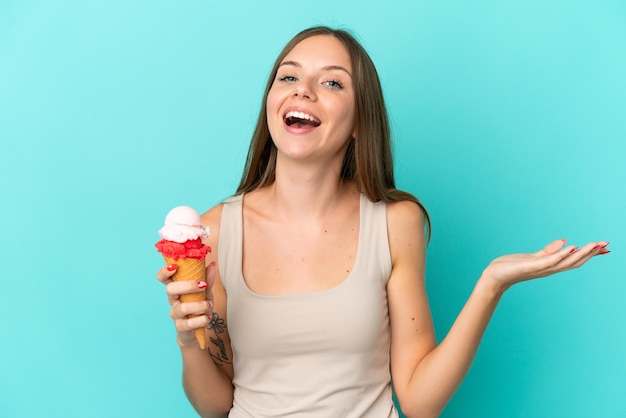 ショックを受けた顔の表情で青い背景に分離されたコルネットアイスクリームと若いリトアニアの女性