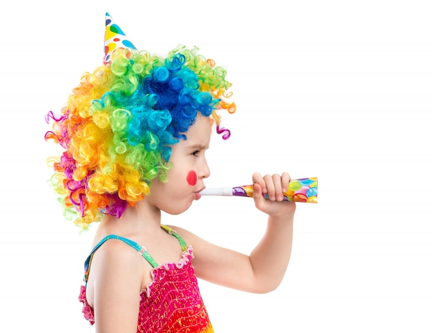 Young little girl in clown wig using party blower