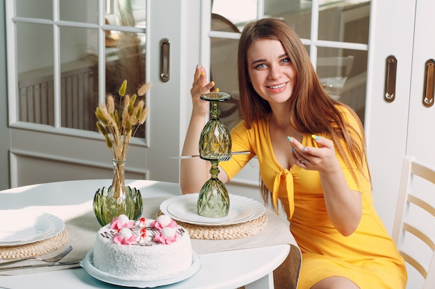 Young lonely woman sitting and boring alone at home or cafe with white birthday cake.