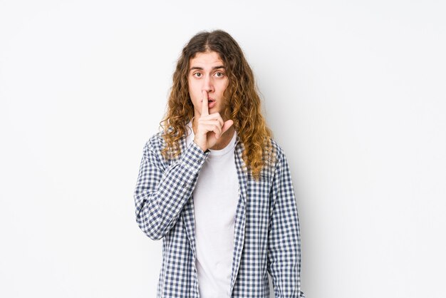 Young long hair man posing isolated keeping a secret or asking for silence.
