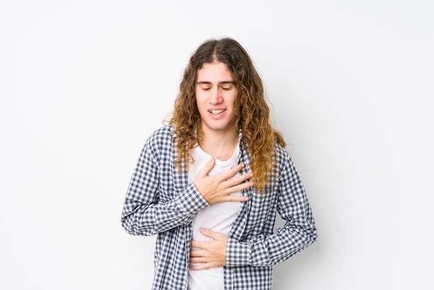 Young long hair man posing isolated laughs happily and has fun keeping hands on stomach.