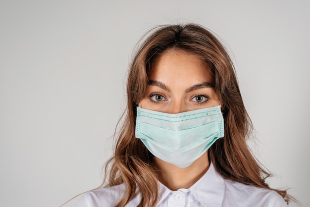 Young longhaired woman in protective medical mask over white background