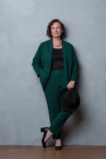 Young looking caucasian lady posing full height in the green stylish suit.