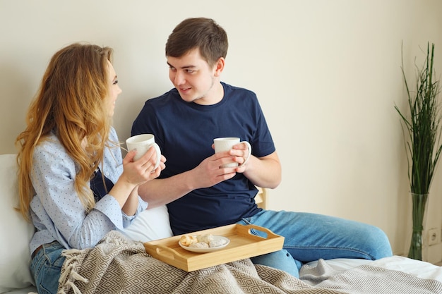 Young lovely couple drinking coffee on bed.