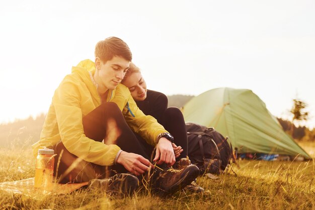 Young lovely couple sitting near tent outdoors at daytime Beautiful sunlight