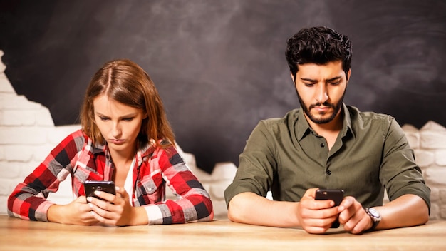 Photo young lovely couple sitting with smartphones