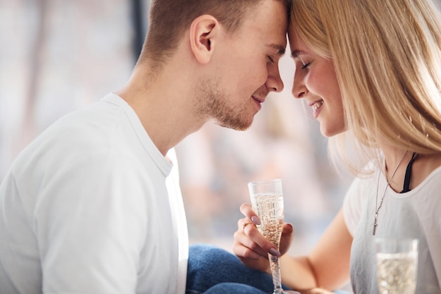 Foto giovani coppie adorabili insieme a casa con champagne che trascorrono il fine settimana e le vacanze insieme