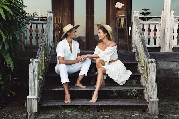 Young lovely couple wearing natural clothes are sitting on the stairs of the porch