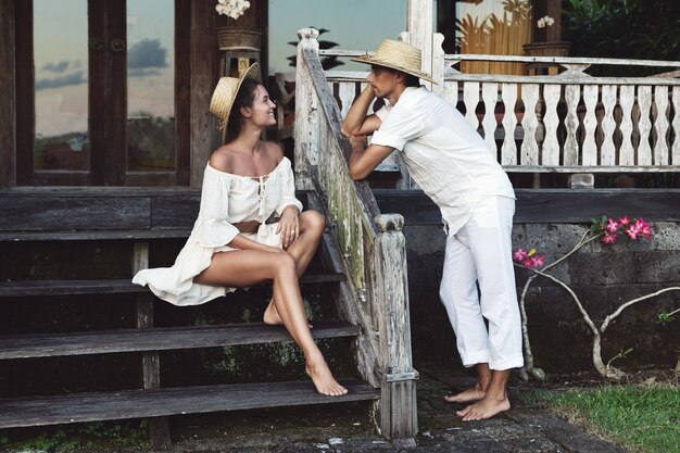 Young lovely couple wearing natural clothes  sitting on the porch of their house