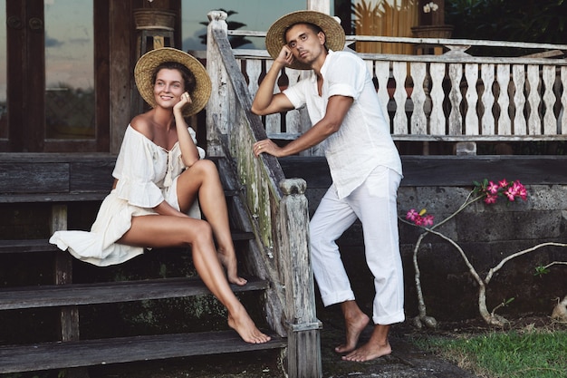 Foto giovane coppia adorabile che indossa abiti naturali seduti sotto il portico della loro casa