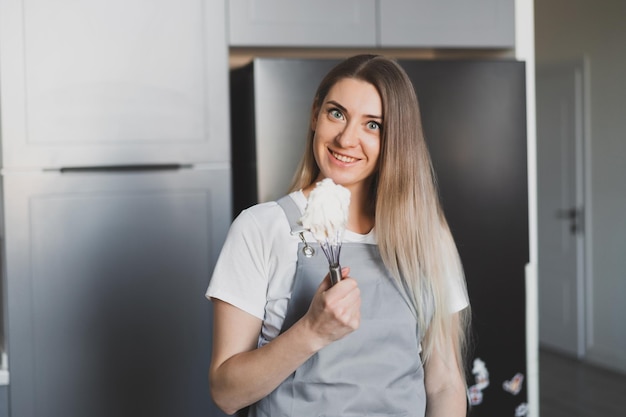 Giovane pasticcere donna adorabile che prepara la crema per torte a casa