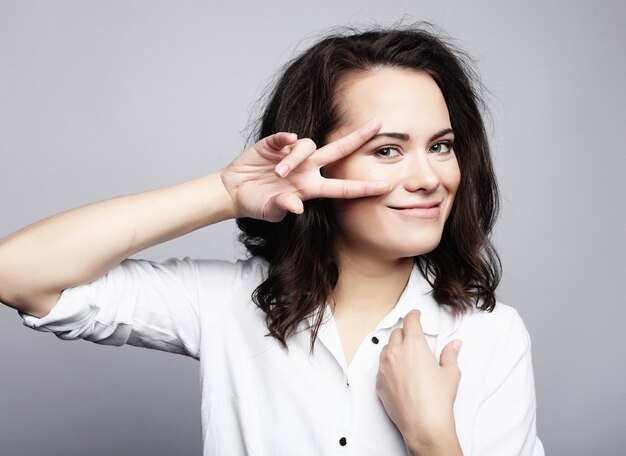 Foto giovane donna adorabile che mostra vittoria o segno di pace