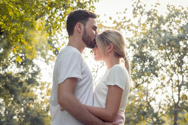 公園でキスする若い恋人たち。 10代のカップルは、公園でお互いに愛を示しています。公園で若いカップルの概念。