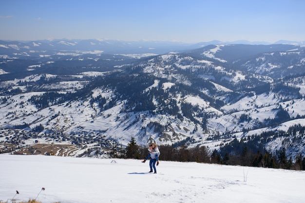 Giovani coppie amorose ad una data nella cima di una montagna innevata