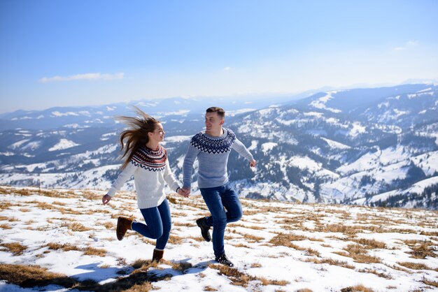 雪をかぶった山の頂上でデートの若い夫婦