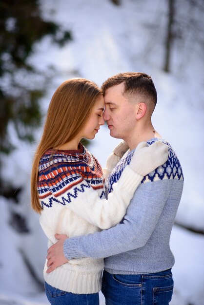 雪をかぶった山の頂上でデートの若い夫婦