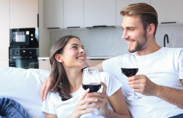 Young loving couple drinking a glass of red wine in their living room