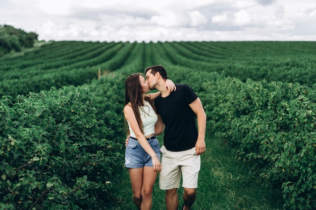 Young loving couple gently hugging on the green currant plantations. Love Story