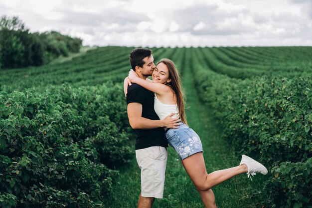 Young loving couple gently hugging on green currant plantations. Love Story