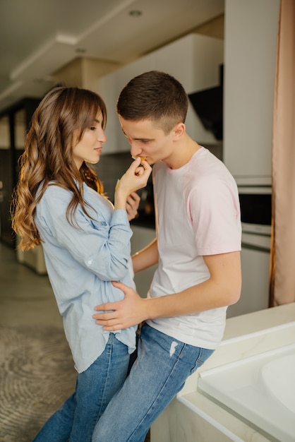 若い夫婦は台所で朝食を持っています。朝食を一緒に楽しんでいるかわいい若いカップル