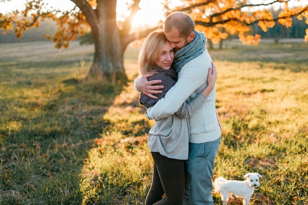 Young loving couple hugging in autumn field at sunset