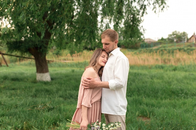 Young loving couple hugging and dancing on the green grass on the lawn