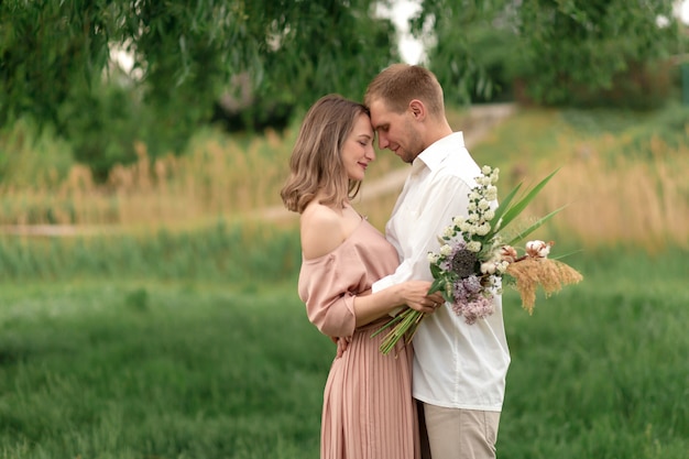 Young loving couple hugging and dancing on the green grass on the lawn