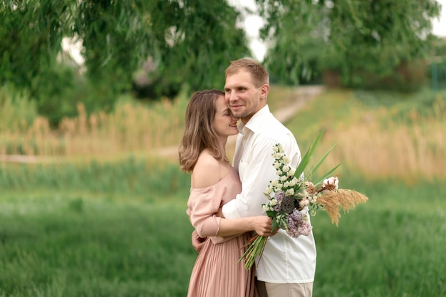 Young loving couple hugging and dancing on the green grass on the lawn