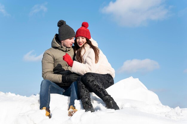 Young loving couple hugs on hugh hill sunny winter day Winter holidays Lot of snow