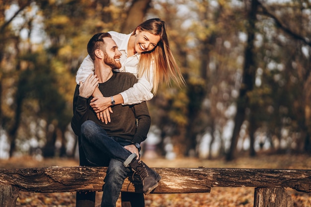 A young loving couple sitting on a wooden bench in the forest.