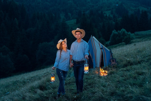 Young loving couple of tourists camping, near a campfire
against the tent at night.