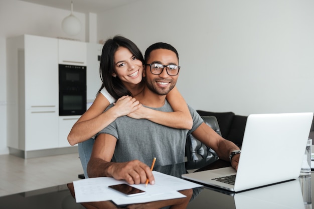 Young loving couple using laptop and analyzing their finances. Looking at the front.