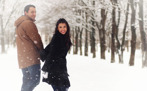 A young loving couple on a walk in a snow park