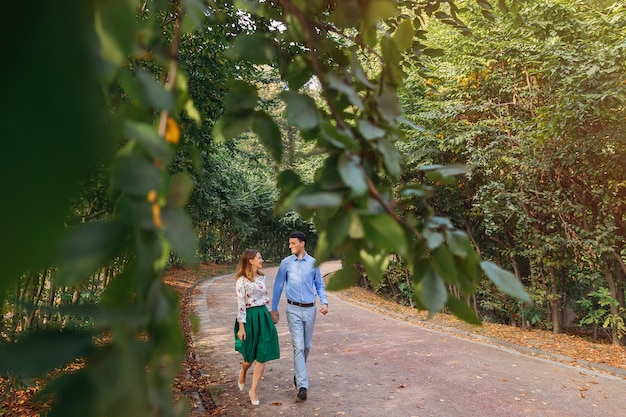 Of a young loving couple walking along a path through a greenery park