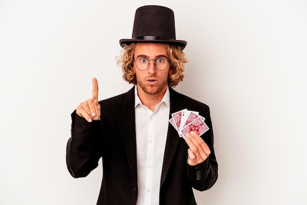 Young magician caucasian man holding magic cards isolated on white background having some great idea, concept of creativity.