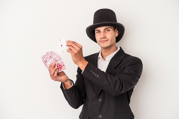 白い背景で隔離の魔法のカードを保持している若いマジシャン白人男性