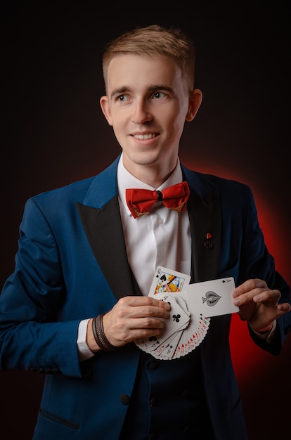 The young magician guy is holding cards in his hands