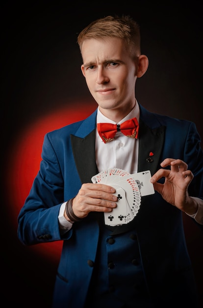 The young magician guy is holding cards in his hands